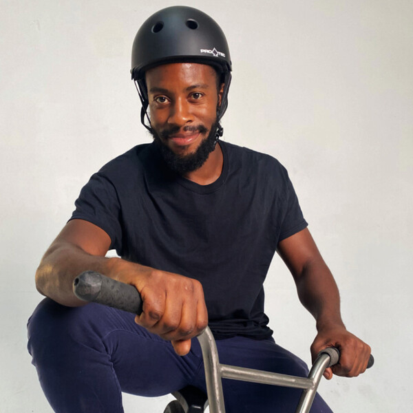 Omari Cato sitzt mit Helm auf einem BMX-Rad und verk&ouml;rpert damit das Radfahren in der Stadt und das Flatland-BMX.